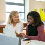 young ethnic female student doing assignment with tutor in university