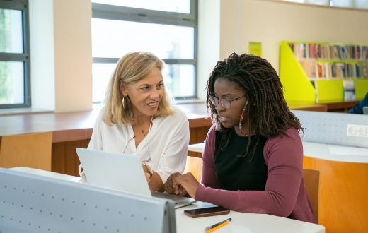 young ethnic female student doing assignment with tutor in university